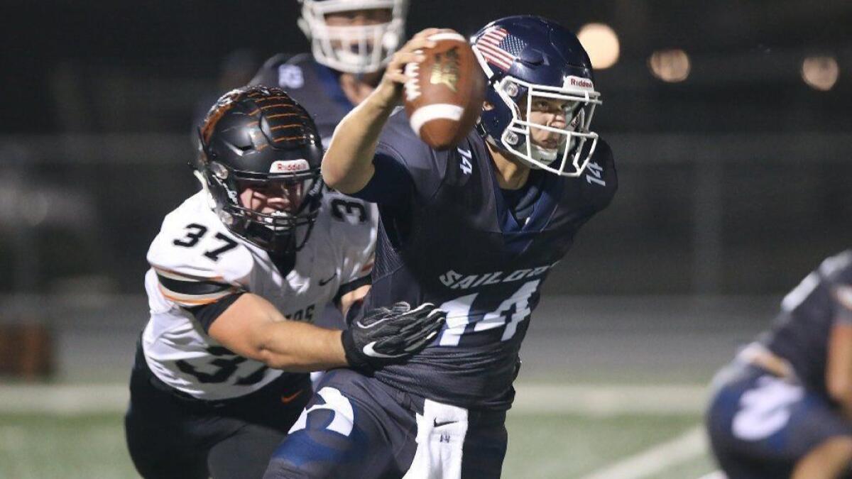 Newport Harbor High quarterback Cole Lavin is wrapped up by Huntington Beach's John Gosney during a Sunset League game on Sept. 28. Gosney has 12½ sacks this season.