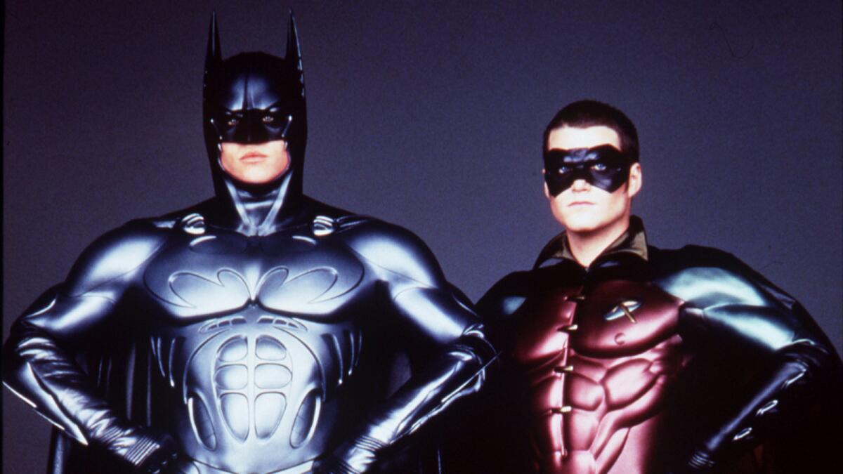 A man in a Batman costume and another man in a Robin costume both with arms akimbo