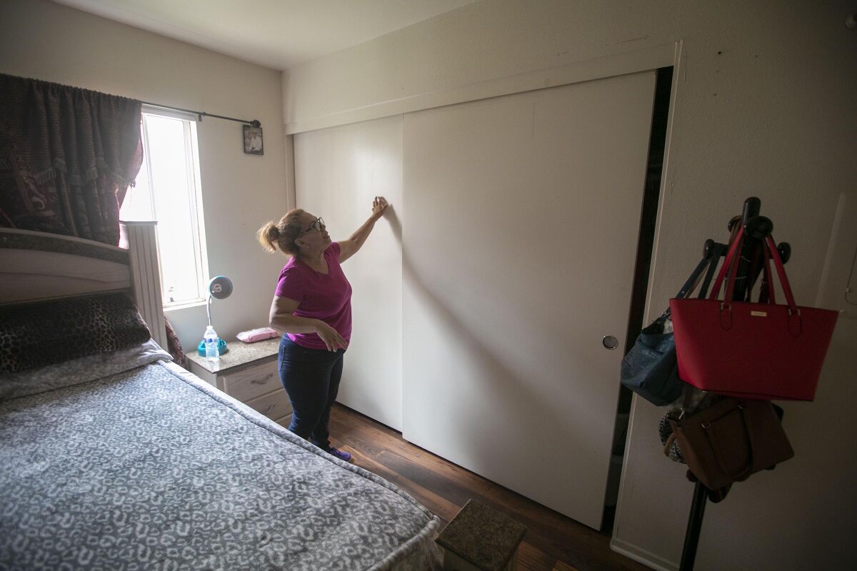 Maria Antonia Albear points to a dysfunctional closet door in her bedroom at Mercado Apartments in Barrio Logan. She says property management is raising her rent by $300 a month in June.