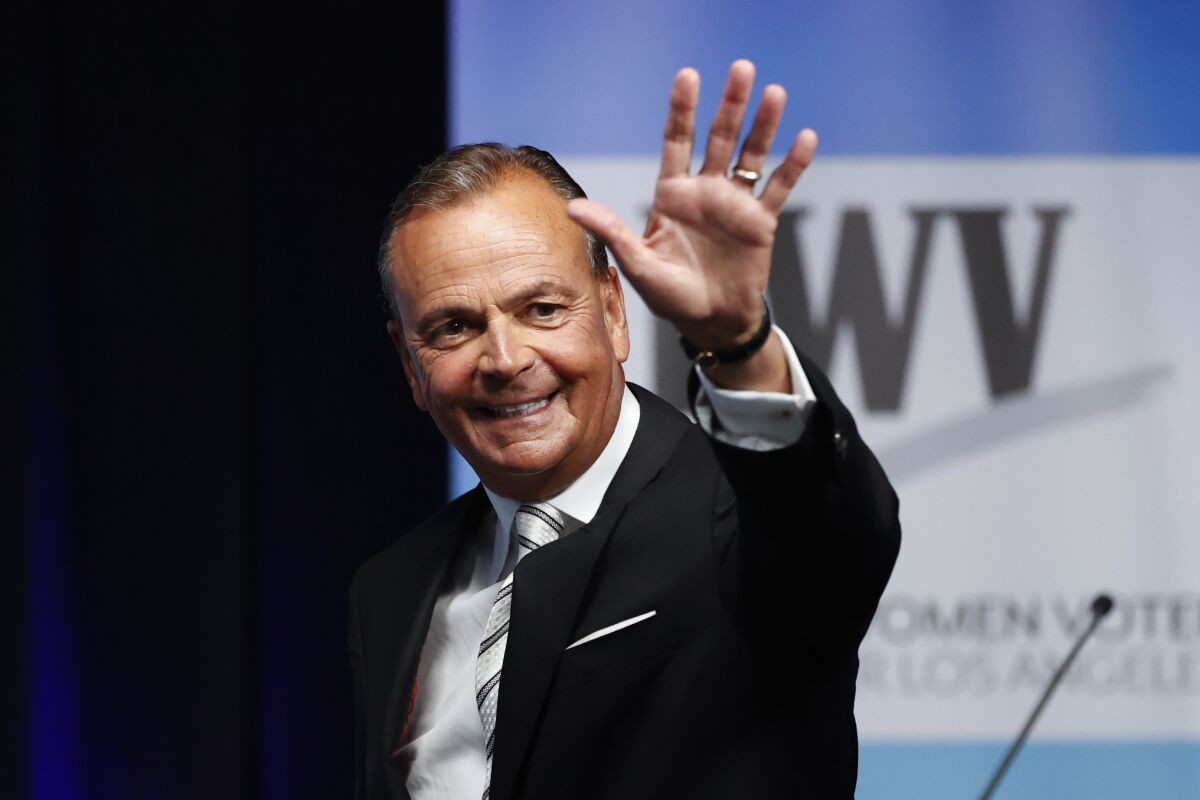 Businessman Rick Caruso waves at the start of a mayoral debate at Cal State Los Angeles on Sunday.