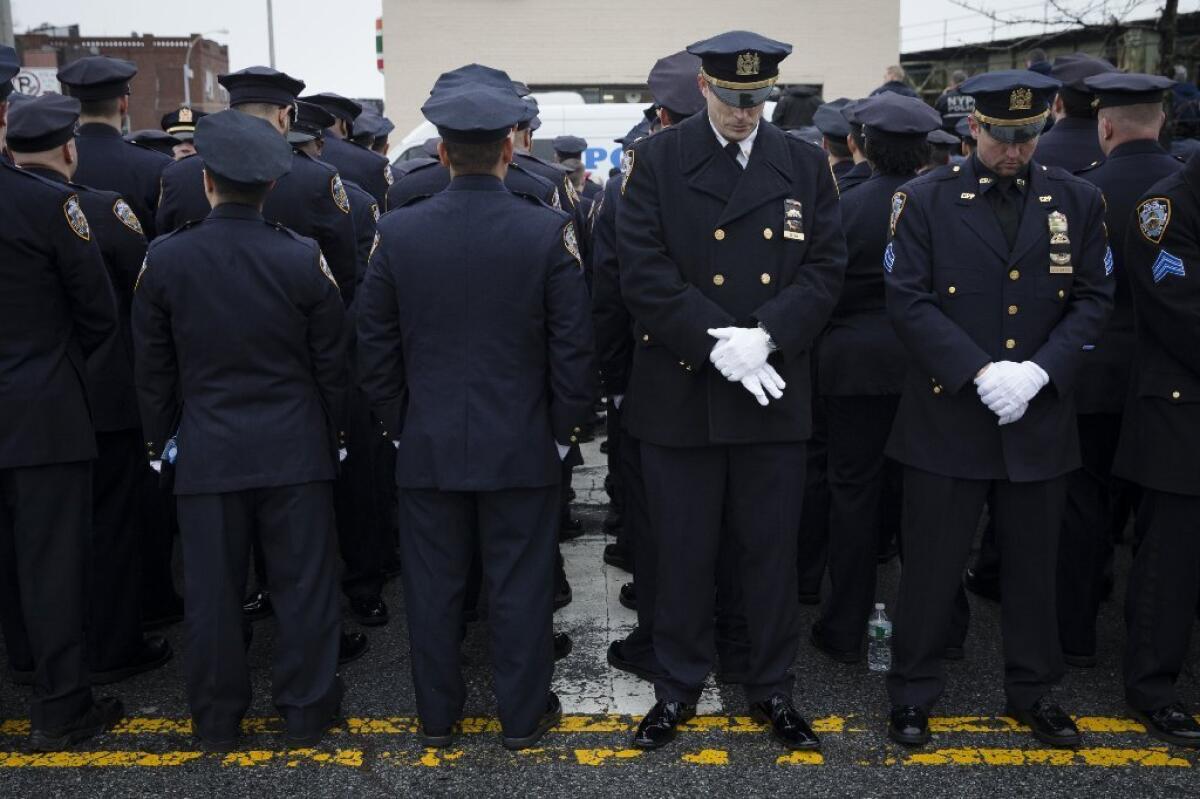 Police officers turn their backs Sunday to screens showing New York Mayor Bill de Blasio speaking at the funeral of Wenjian Liu, one of two policemen slain Dec. 20.