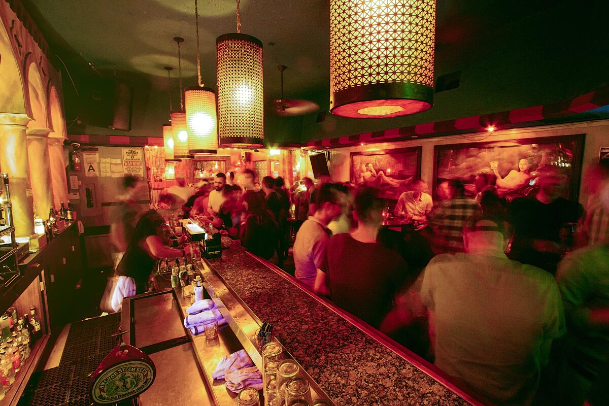 People standing along a long bar in a small club