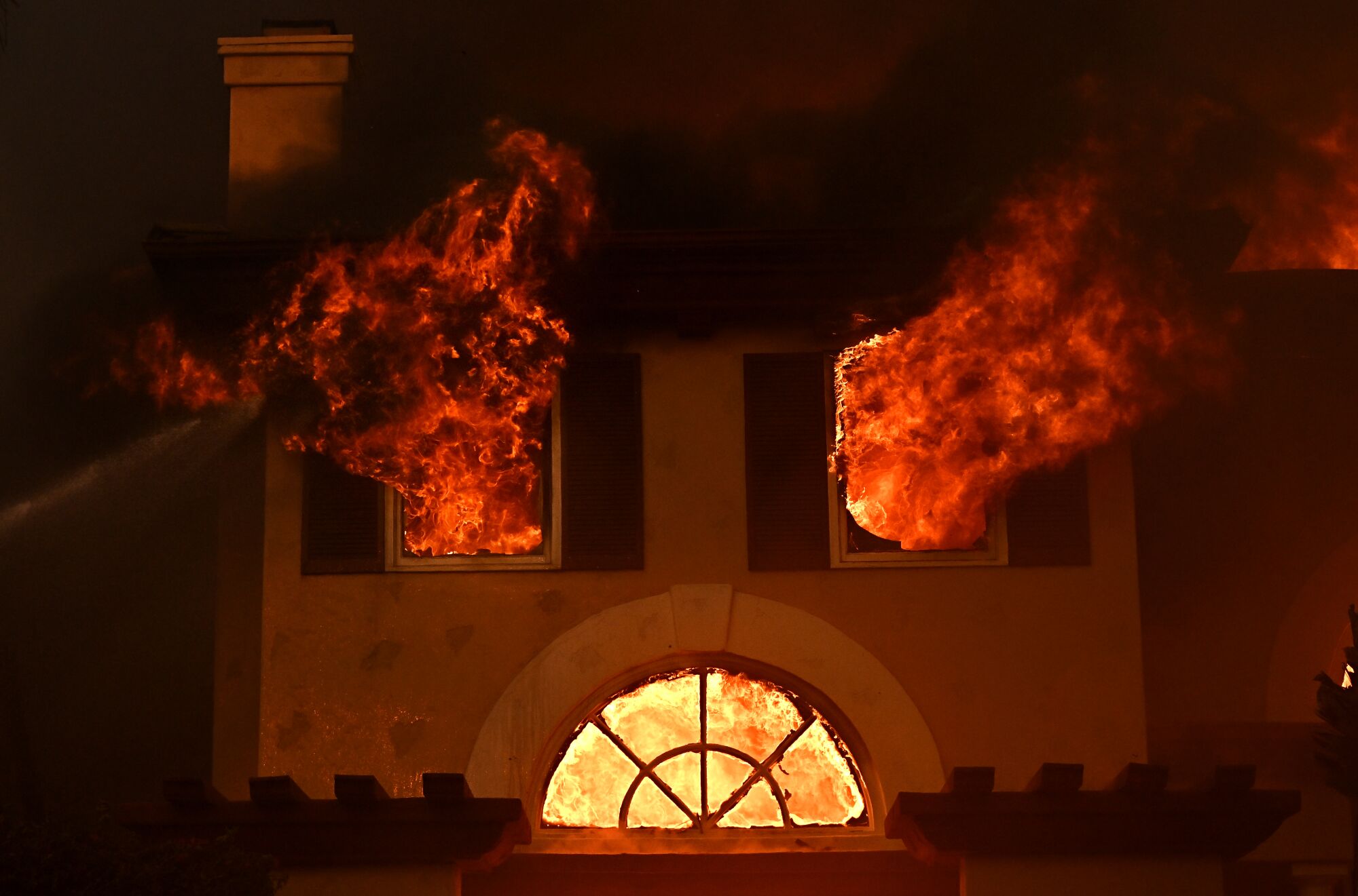 Flames shoot from the windows of a burning home