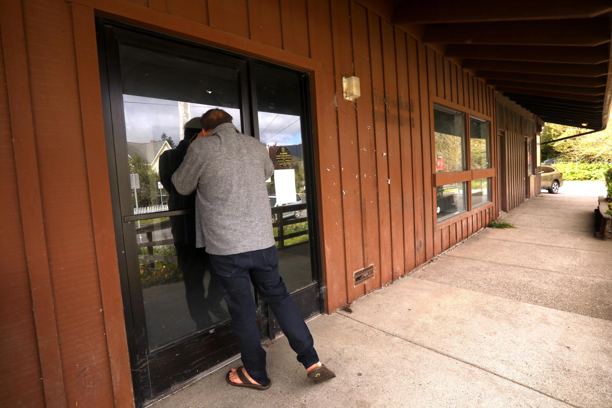 A man peers through the window of a shuttered building.