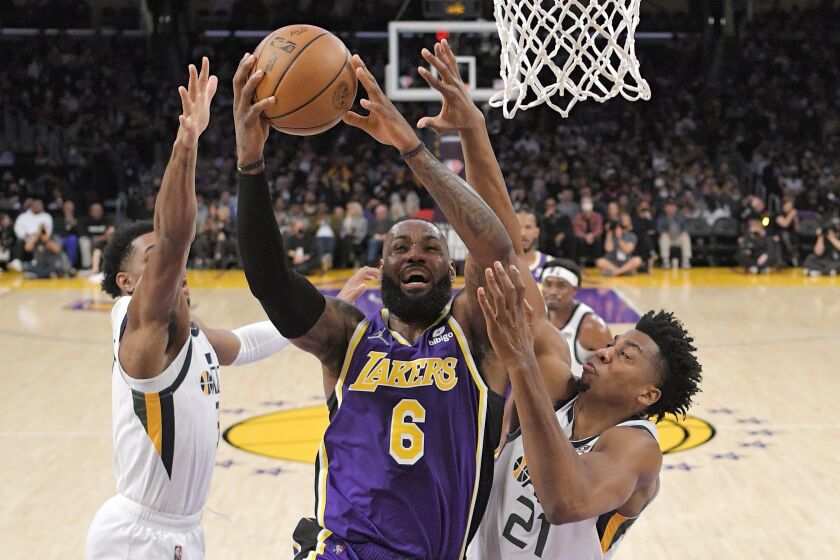 Los Angeles Lakers forward LeBron James, center, shoots as Utah Jazz guard Trent Forrest, left, and center Hassan Whiteside defend during the first half of an NBA basketball game Wednesday, Feb. 16, 2022, in Los Angeles. (AP Photo/Mark J. Terrill)