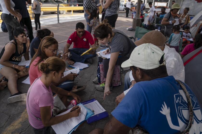 Volunteer lawyer Henriette Vinet-Martin, center, shows asylum seekers that have been sent back to wait in Mexico under the Migrant Protection Protocols, how to fill out their asylum claim forms during a workshop on Saturday, Aug. 24, 2019 in Matamoros, Tamaulipas. Verónica G. Cárdenas for Los Angeles Times