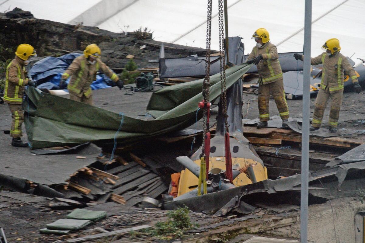 Rescuers position a tarp over the wreckage of a police helicopter that plunged through the roof of the Clutha Vaults pub in Glasgow, Scotland, on Dec. 2, 2013, after its engines failed.