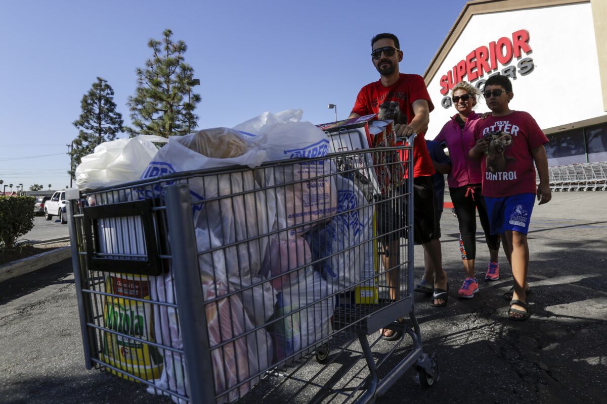 Pablo DeLaTorre, his wife, Maria Ruiz, and their two sons walk out of the Superior Grocers supermarket in Compton with a full cart of groceries.