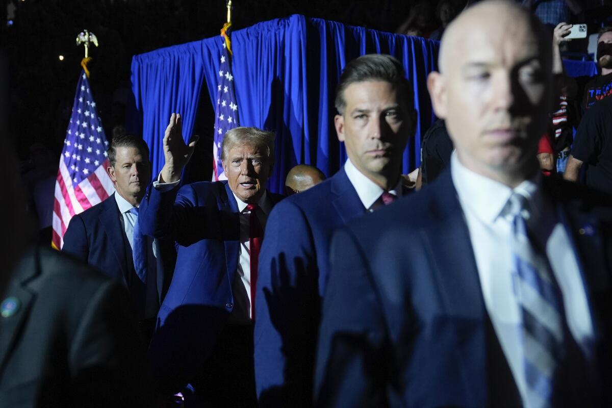 Donald Trump and other men on a stage with U.S. flags behind them. 