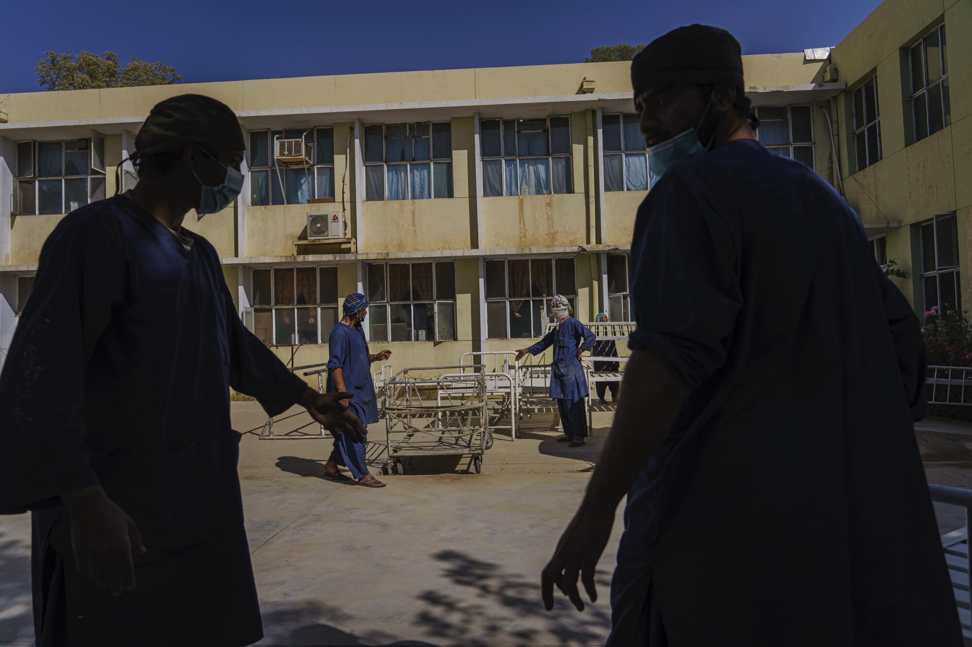 Hospital workers prepare beds and tents outdoors.