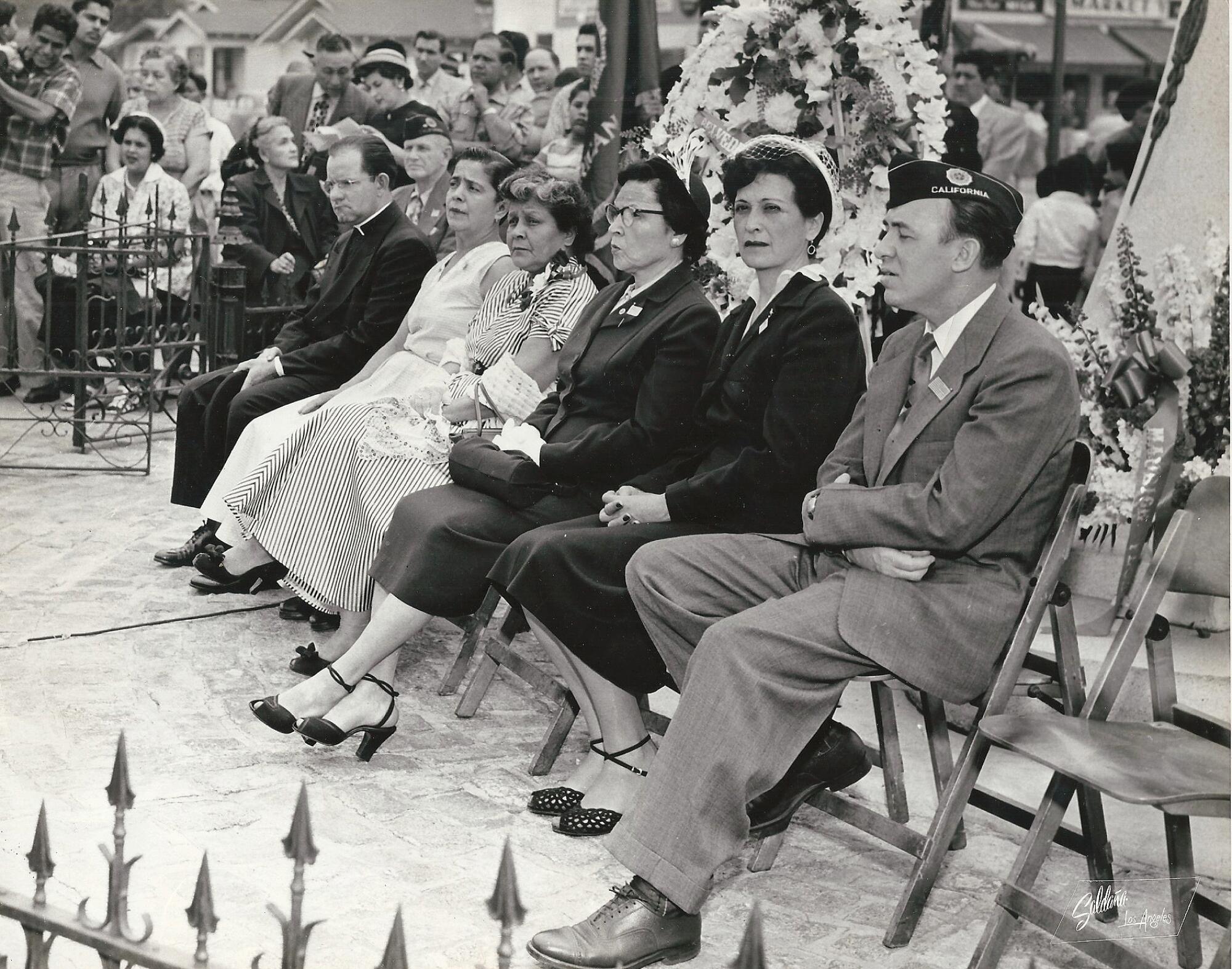 People sit in folding chairs at a ceremony