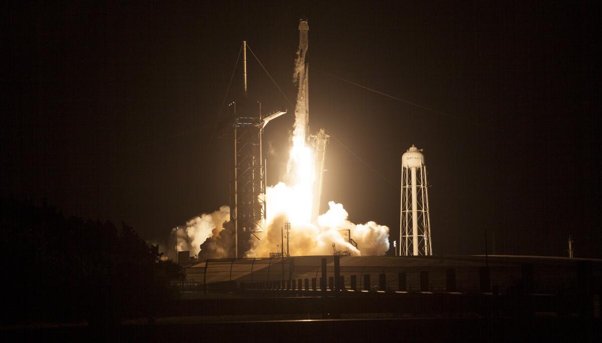 A SpaceX rocket lifts off from a launch pad.