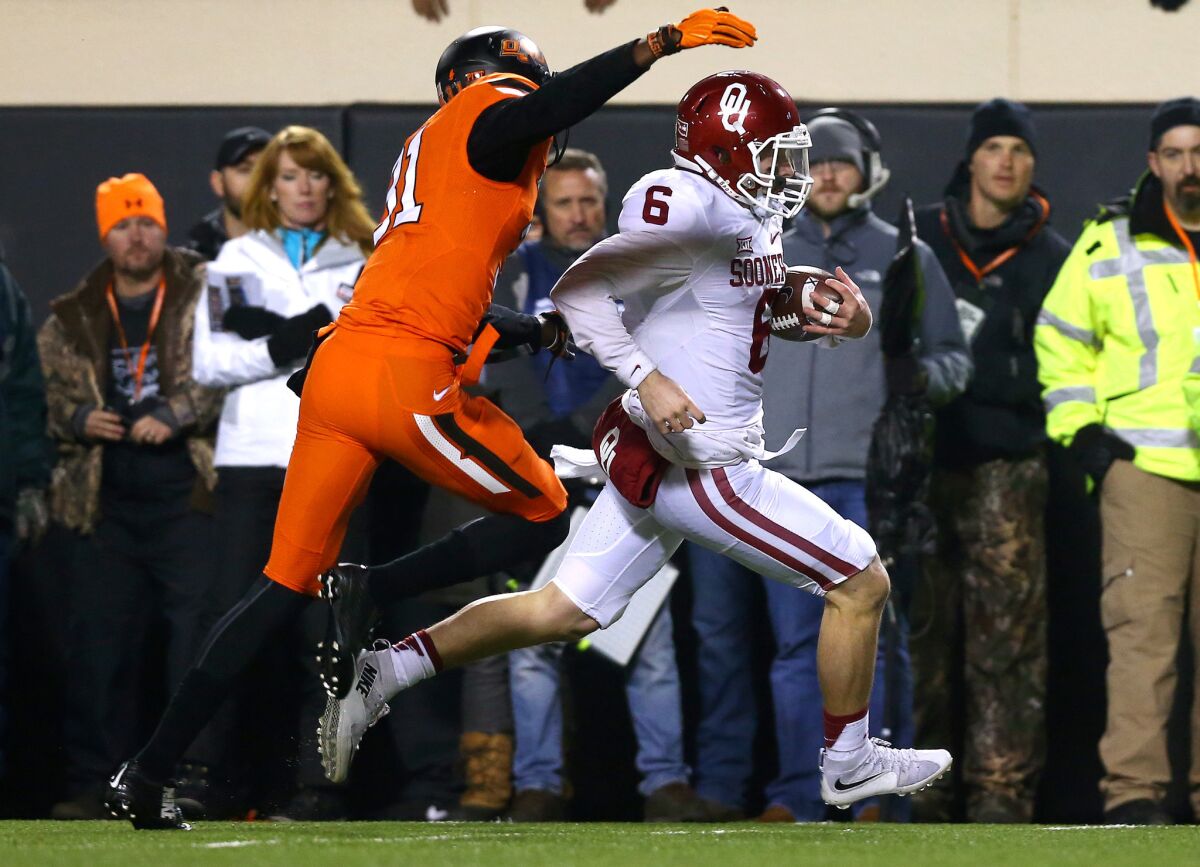 Oklahoma's Baker Mayfield rushes past Oklahoma State's Tre Flowers on Saturday.