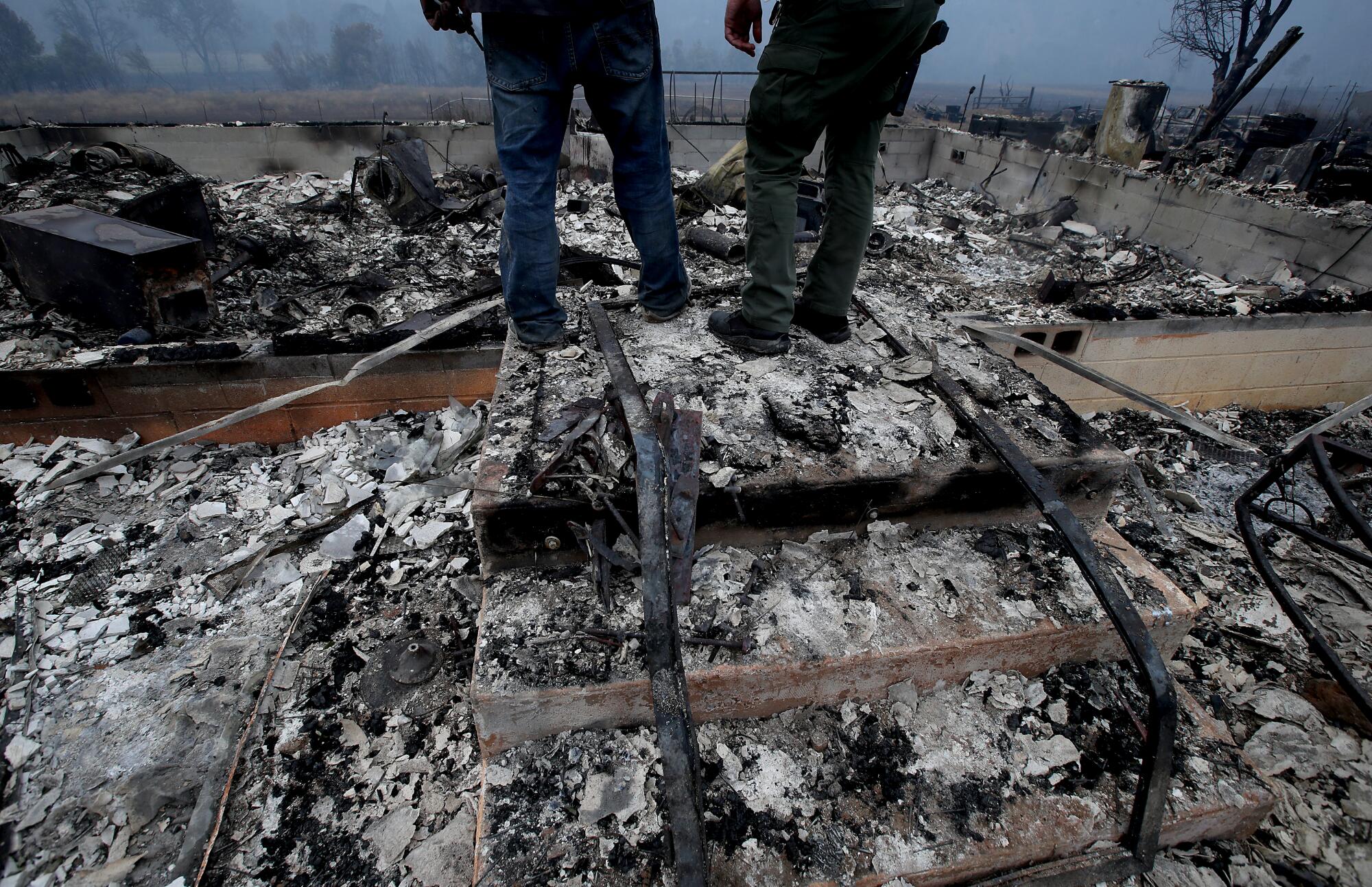 People look over a burned home in the Mckinney Fire near Yureka.