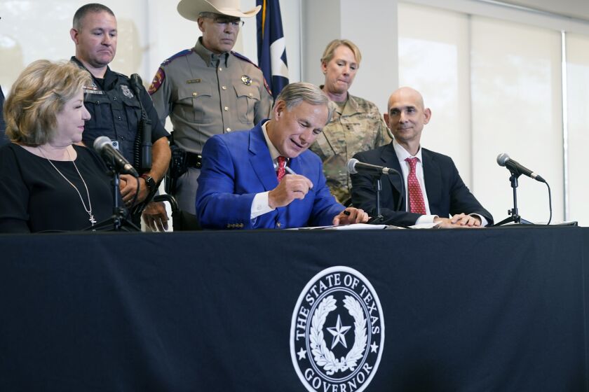 FILE - Texas Gov. Greg Abbott, front center, is flanked by state Sen. Jane Nelson, R-Flower Mound, front left, and Rep. Greg Bonnen, R-Friendswood, front right, with others looking on as he signs a bill that provides additional funding for security at the U.S.-Mexico border on Sept. 17, 2021, in Fort Worth, Texas. Abbott on Tuesday, Dec. 6, 2022, named Nelson, a longtime GOP lawmaker with a record of bipartisan appeal, as his choice to become the state's new election chief after facing blowback and scrutiny over his past picks to oversee voting. (AP Photo/LM Otero, File)