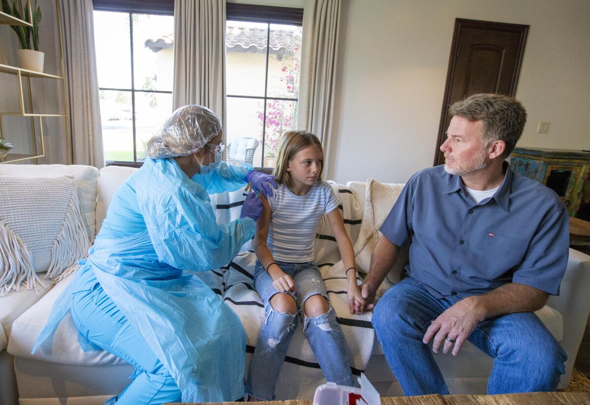 Denise Abalos gives a shot to Amber Sievers as her father Jeff holds her hand.