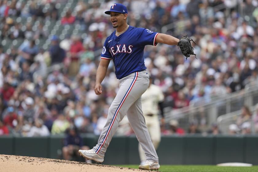 Texas Rangers starting pitcher Gerson Garabito reacts after issuing a walk to Minnesota Twins' Carlos Santana during the fourth inning of his Major League debut of a baseball game Sunday, May 26, 2024, in Minneapolis. (AP Photo/Abbie Parr)