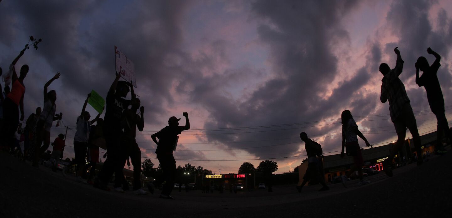In this photo taken with a fisheye lens, people protest after the fatal shooting by police of Michael Brown in Ferguson, Mo. Brown's shooting has sparked more than a week of protests, riots and looting in the St. Louis suburb.