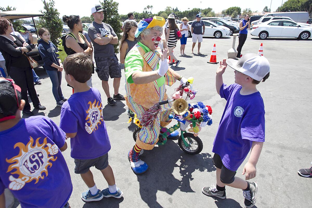Ravioli the clown high-fives kids from a Westminster summer camp as they get in line to attend the OC Fair on Thursday.