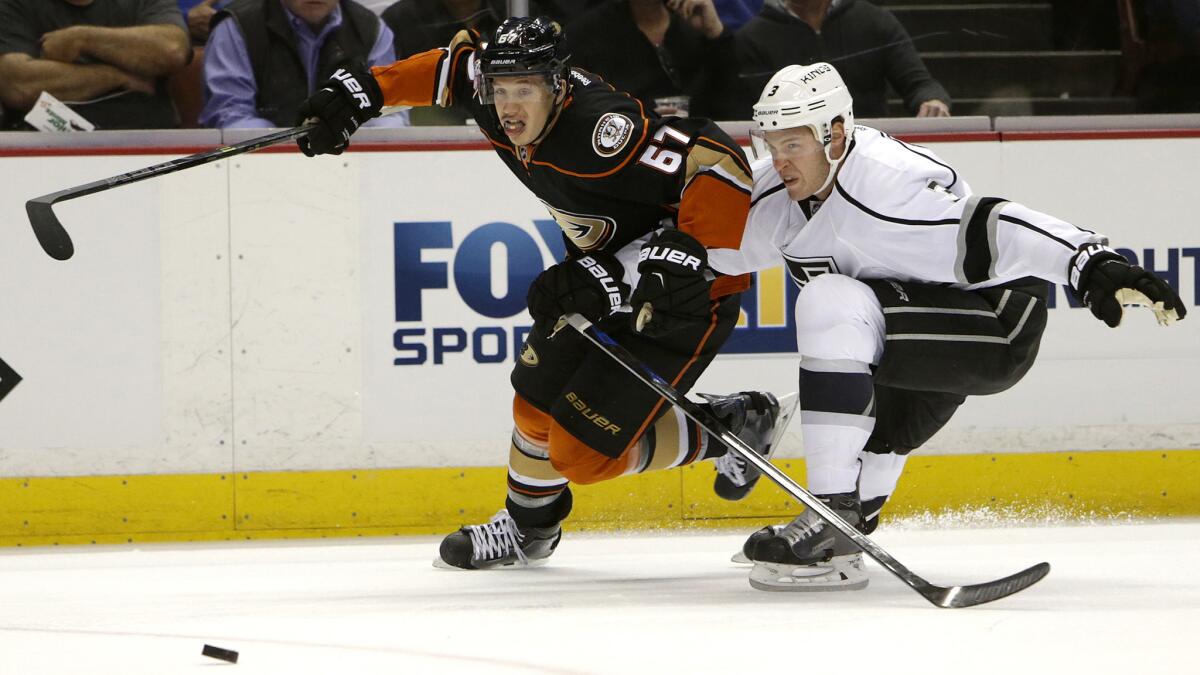Kings defenseman Brayden McNabb fights for position with Ducks center Rickard Rakell (67) as they chase down the puck.