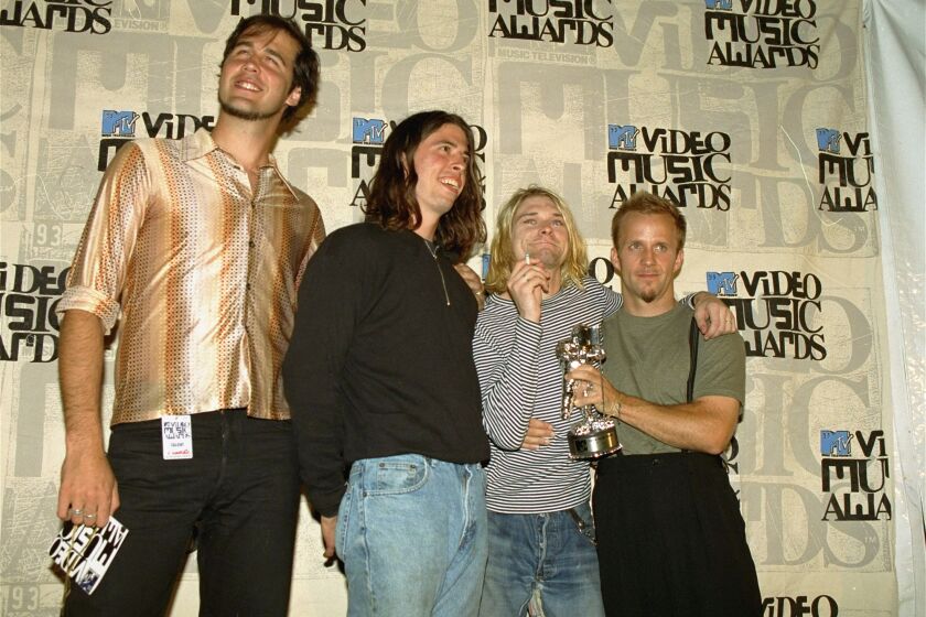 FILE - In this Sept. 2, 1993 file photo, Nirvana band members, Chris Novoselic, from left, Dave Grohl, and Kurt Cobain pose, with an unidentified man, right, after receiving an award for best alternative video for "In Bloom" at the 10th annual MTV Video Music Awards in Universal City, Calif. Cobain’s widow and daughter are urging a Seattle judge not to release death-scene photos and records that a lawsuit claims will prove the Nirvana frontman was murdered more than 20 years ago. Superior Court Judge Theresa Doyle is set to hear arguments Friday, July 31, 2015, over whether to proceed with a trial after Richard Lee, who runs a Seattle public access TV show, sued the city and the Seattle Police Department for the material he says will show Cobain didn’t die of a self-inflicted gunshot wound in 1994, The Seattle Times reported. (AP Photo/Mark J. Terrill, File)