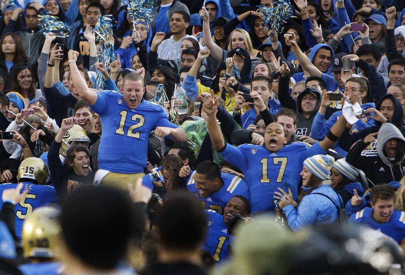 Bruins quarterbacks Richard Brehaut (12) and Brett Hundley (17) celebrate with fans after their 38-28 victory over the Trojans on Saturday at the Rose Bowl.