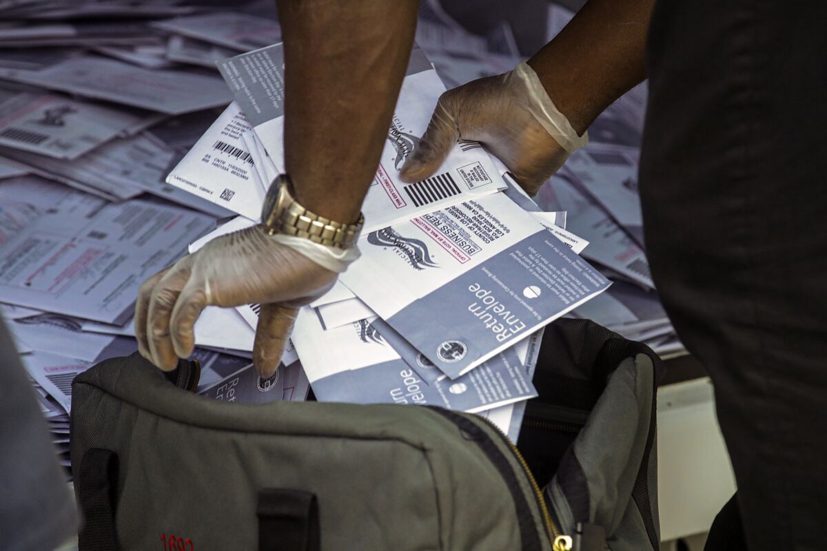 An L.A. County worker collect ballots from a drop box 