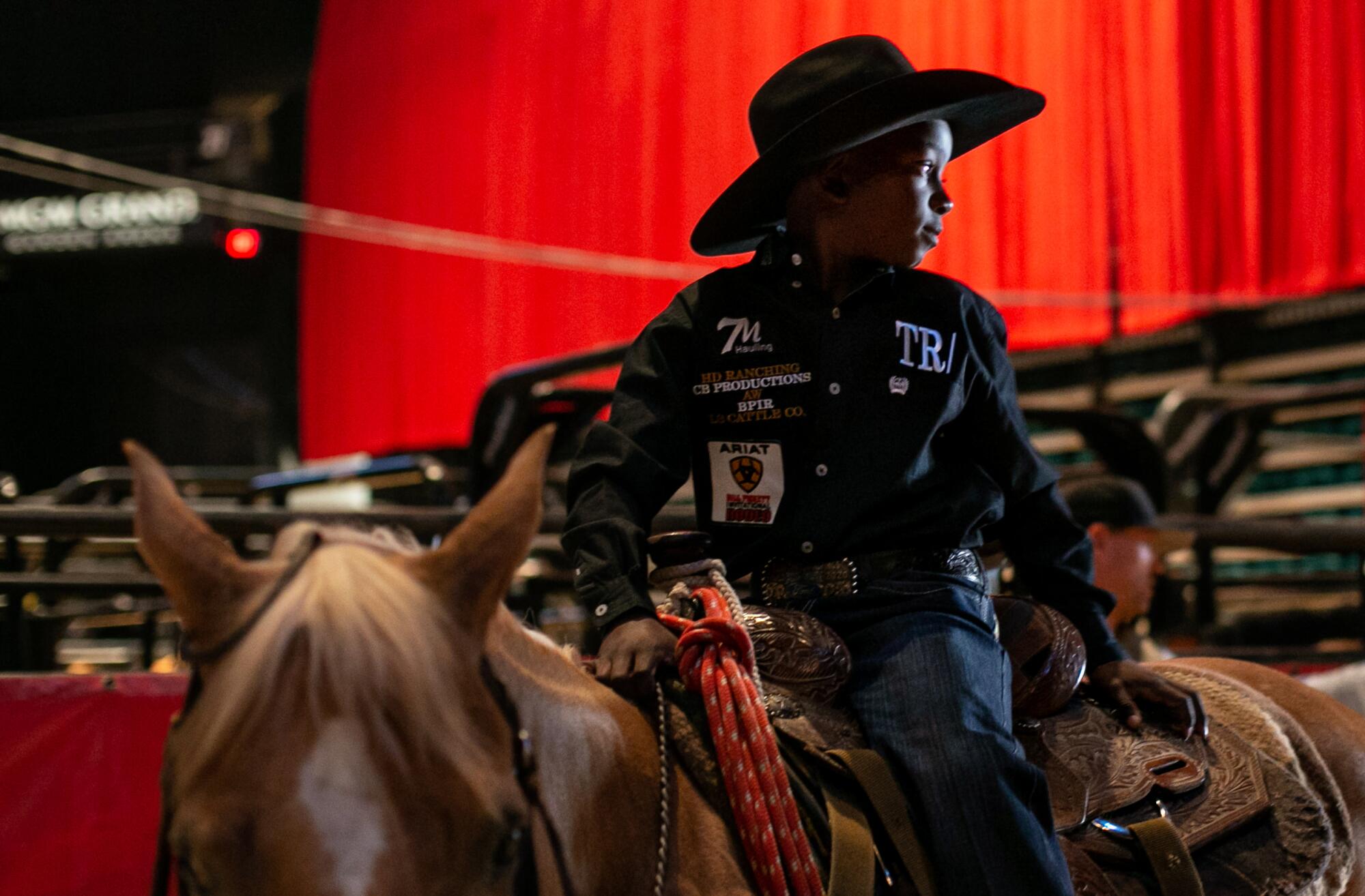 A young cowboy sits on his horse