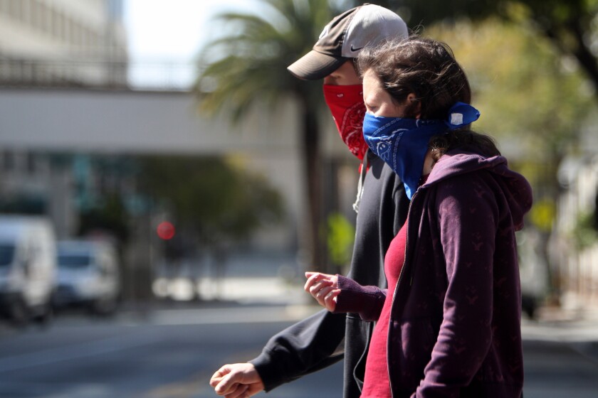A couple wear bandanas as they walk on E. Broadway at Artsakh Ave., in Glendale on Tuesday, April 14, 2020.