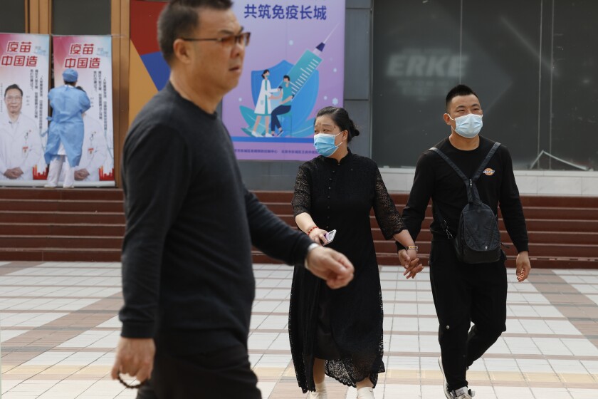 Chinese residents, some wearing masks, pass by a coronavirus vaccination center in Beijing Friday, April 9, 2021. In a rare admission of the weakness of Chinese coronavirus vaccines, the country's top disease control official says their effectiveness is low and the government is considering mixing them to give them a boost. (AP Photo/Ng Han Guan)