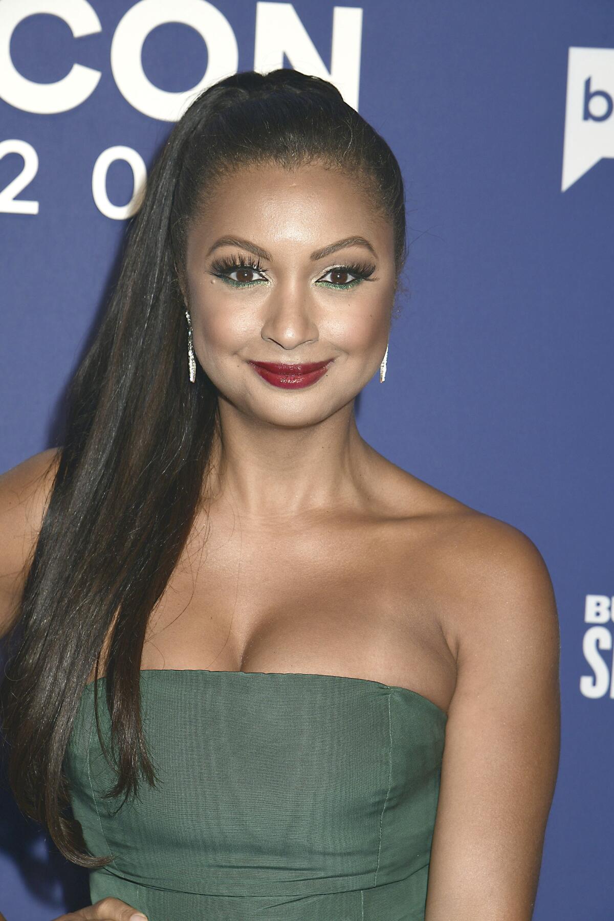 Eboni K. Williams wears a strapless green gown and diamond earrings with a high ponytail
