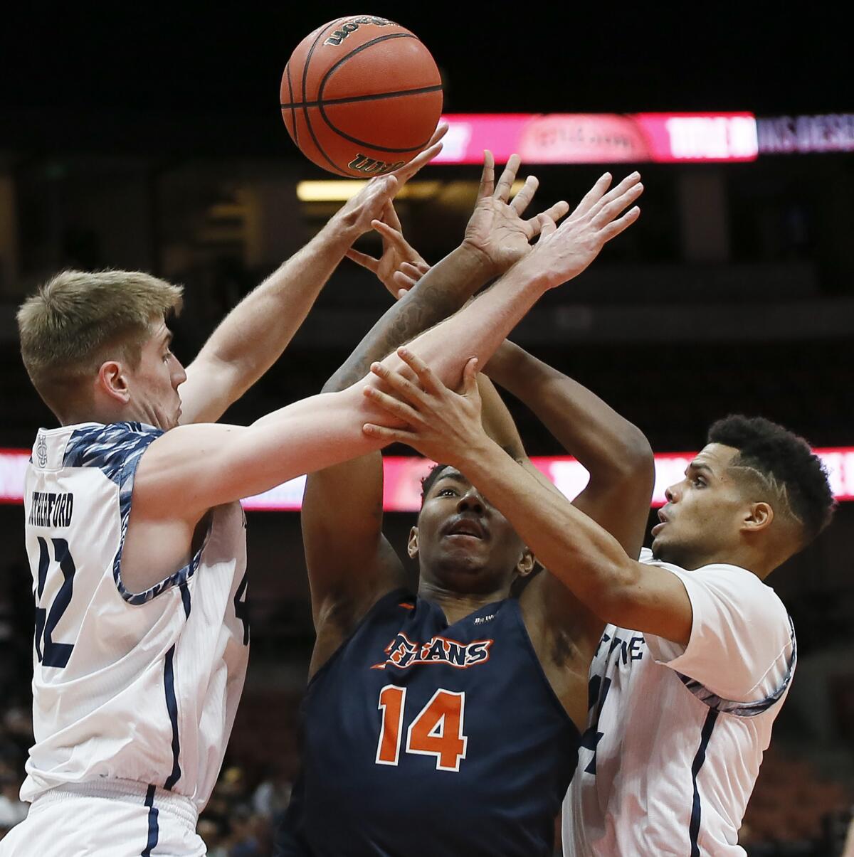 Cal State Fullerton guard Khalil Ahmad, center, battles for a loose ball against UC Irvine's Tommy Rutherford, left, and Evan Leonard during the first half of the Big West men's tournament championship in Anaheim.