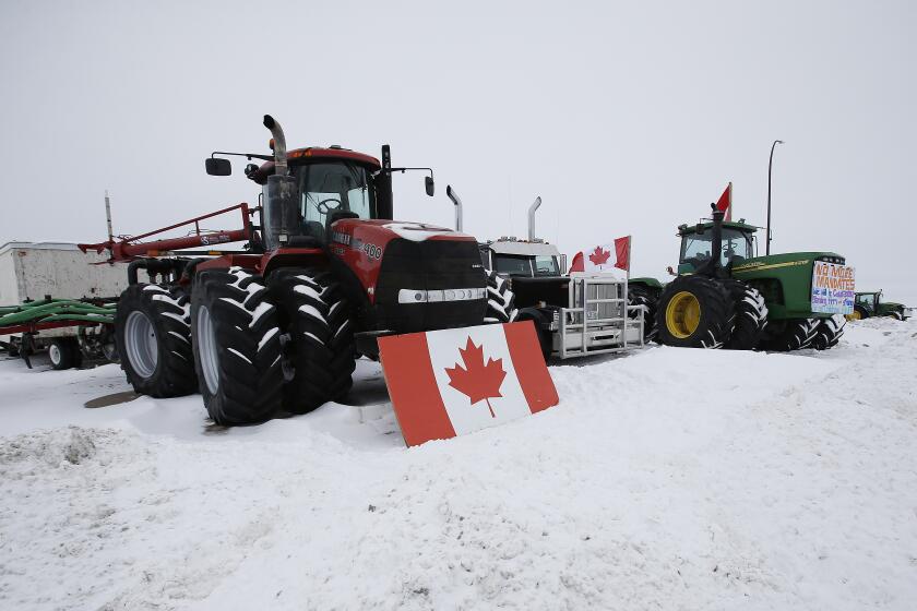 People block highway 75 with heavy trucks and farm equipment and access to the Canada-United States border crossing at Emerson, Manitoba, Thursday, Feb. 10, 2022. The blockade was set up to rally against provincial and federal COVID-19 vaccine mandates and in support of Ottawa protestors. (John Woods/The Canadian Press via AP)