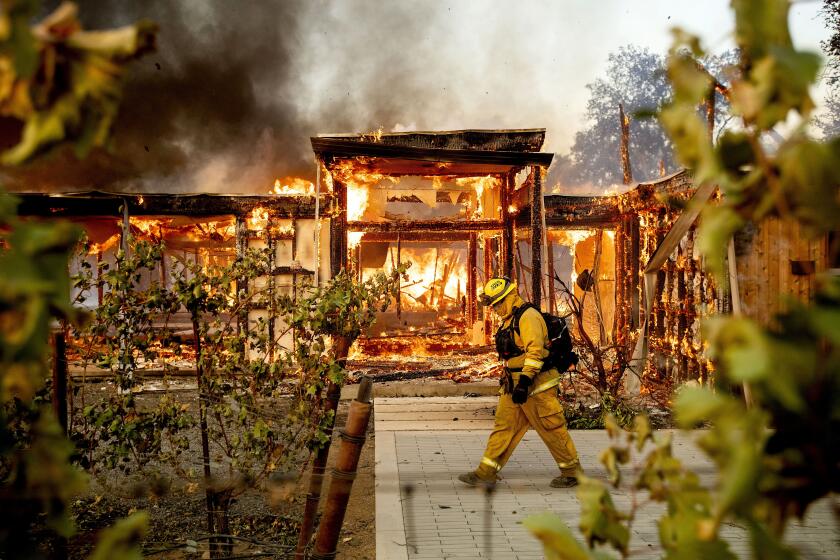 FILE - Woodbridge firefighter Joe Zurilgen passes a burning home as the Kincade Fire rages in Healdsburg, Calif., on Oct. 27, 2019. California Insurance Commissioner Ricardo Lara announced plans on Thursday, Sept. 21, 2023, aimed at keeping home insurers in California amid increasing risks from climate change. (AP Photo/Noah Berger, File)