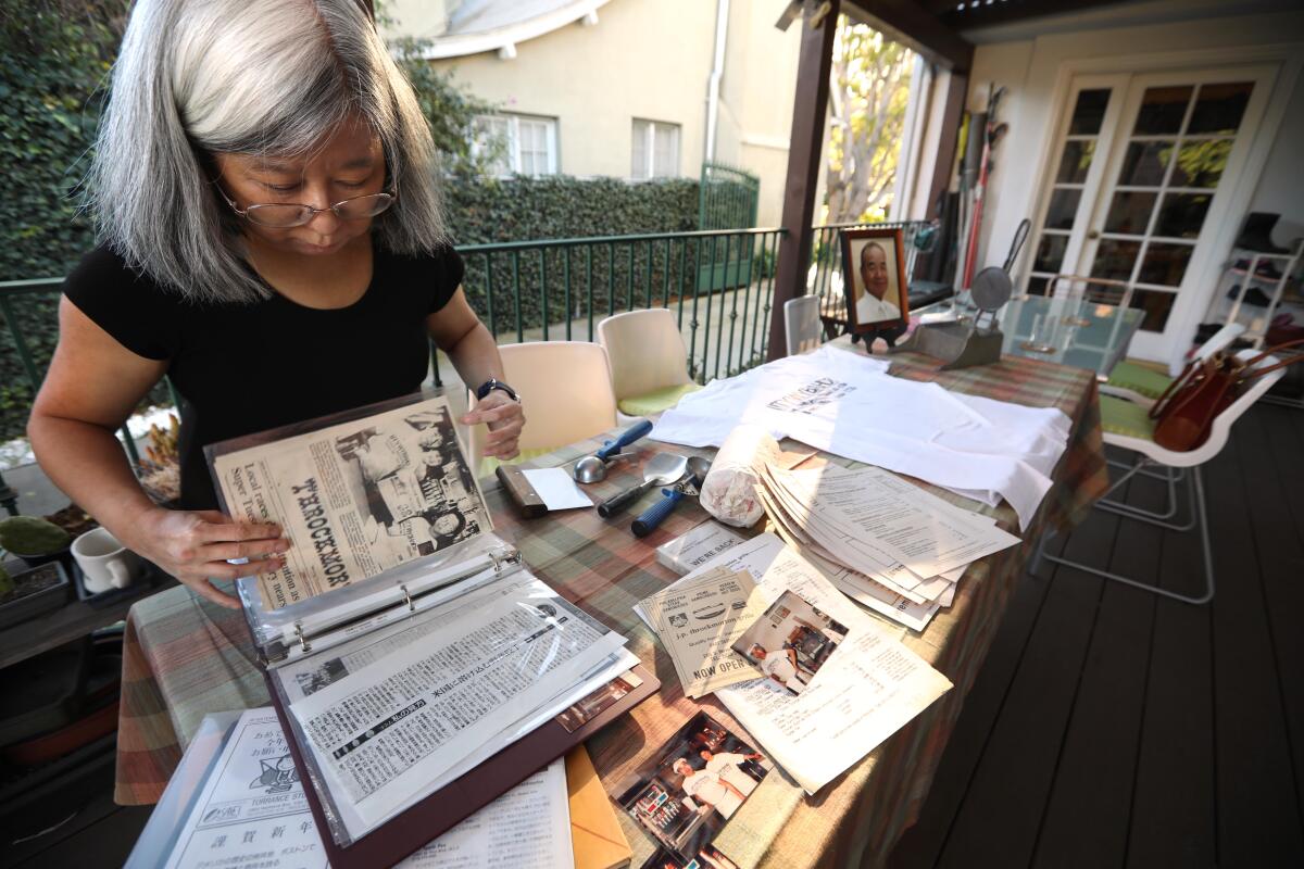 Takako Nagumo examines keepsakes from her family's shuttered restaurant, Jeremiah P. Throckmorton Grille.