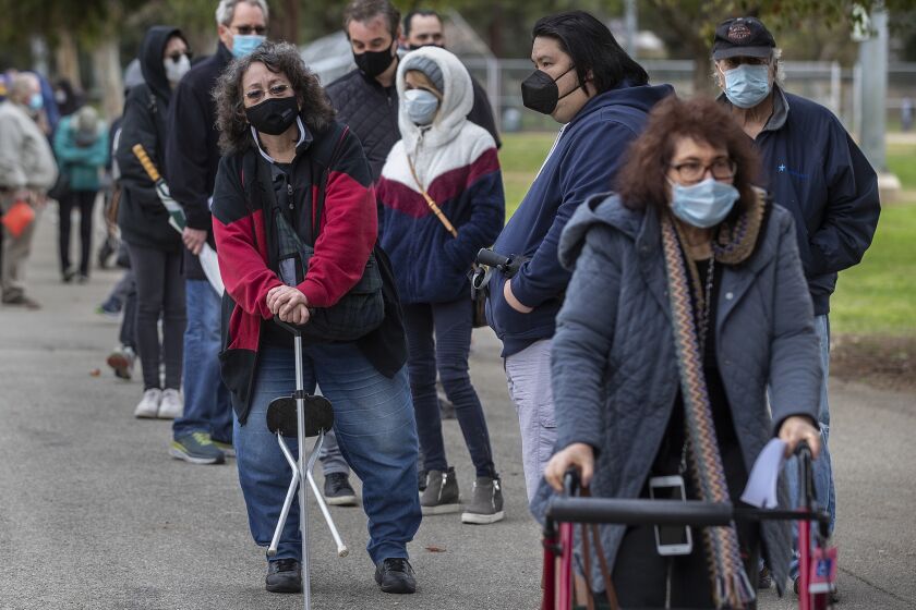ENCINO, CA - JANUARY 27, 2021:Valerie Dunlap, 67, left, of Granada Hills, and Cookie Lewis, 68, right, of Valley Village, make their way with others in the by appointment only line to get vaccine shots to protect against the coronavirus at the Balboa Sports Complex in Encino. (Mel Melcon / Los Angeles Times)
