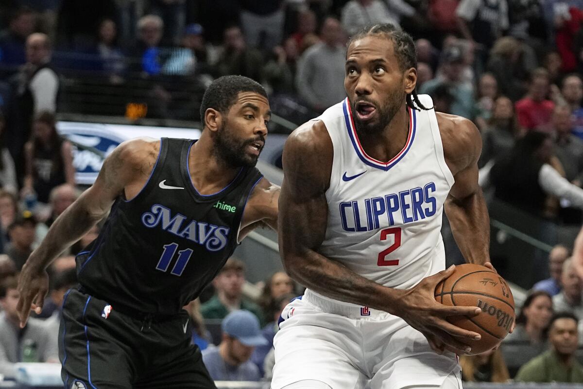 Clippers forward Kawhi Leonard, right, gathers the ball as he prepares to shoot after driving past Dallas guard Kyrie Irving.