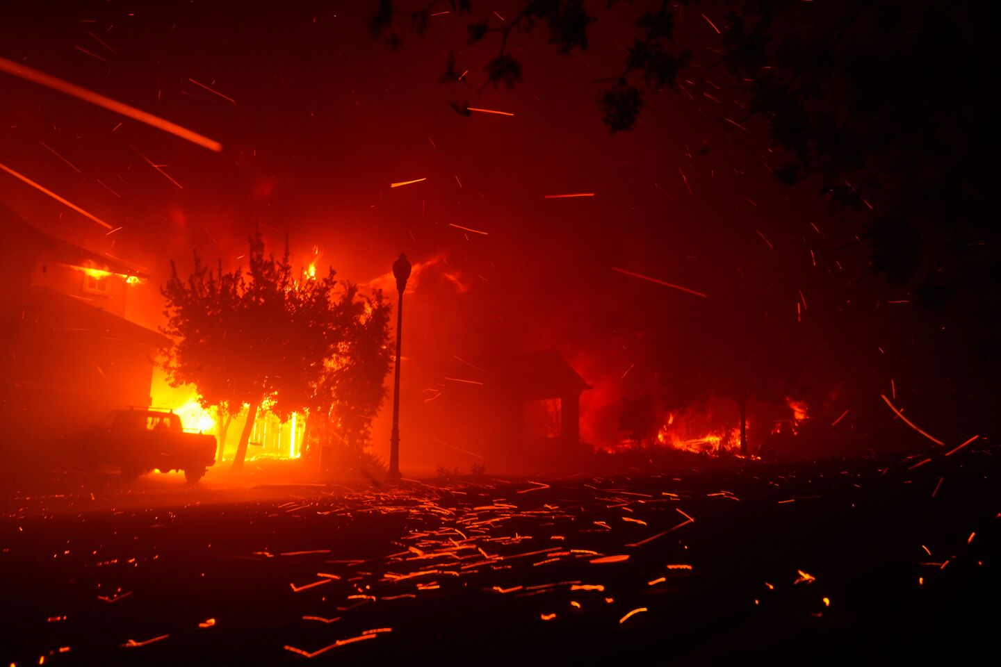 Embers streak the night sky and litter the ground as a home burns in Santa Rosa.