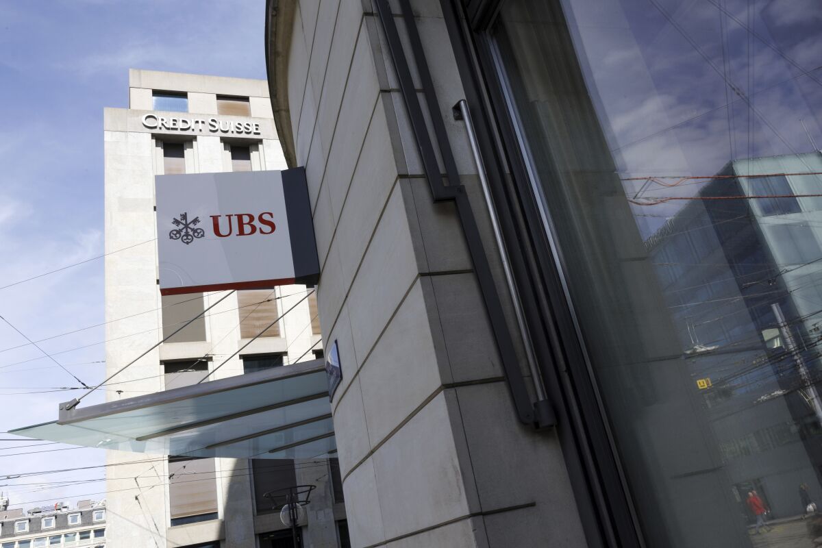The logos of the Swiss banks UBS and Credit Suisse are displayed on different buildings in Geneva, Switzerland, Monday, March 20, 2023. Shares of Credit Suisse plunged 60.5% on Monday after banking giant UBS said it would buy its troubled Swiss rival for almost $3.25 billion in a deal orchestrated by regulators to try to stave off further turmoil in the global banking system. (Salvatore Di Nolfi/Keystone via AP)