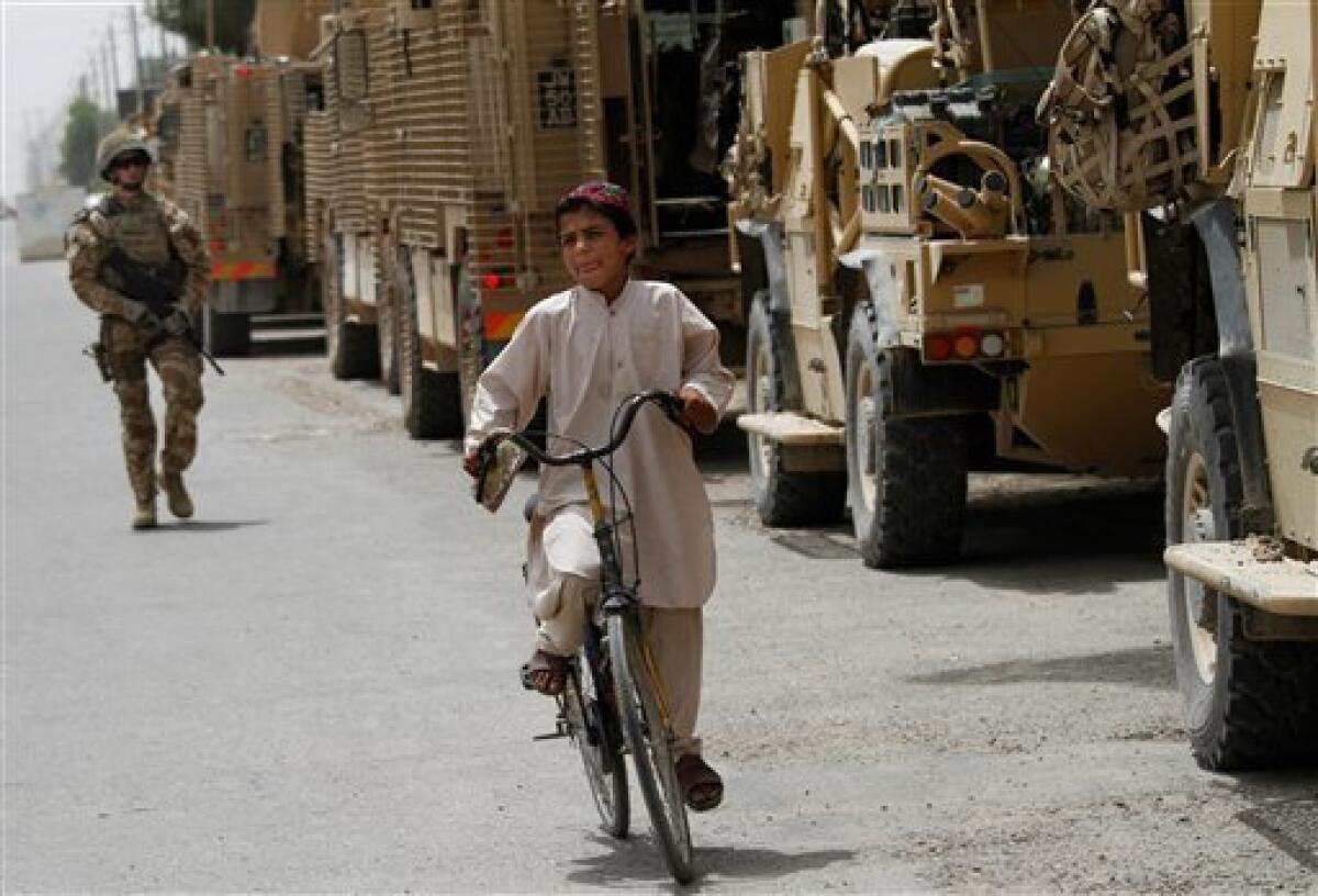 An Afghan boys rides a bicycle past British armored vehicles in Lashkar Gah, Helmand province, south of Kabul, Afghanistan, May 1, 2010. (AP Photo/Dar Yasin)