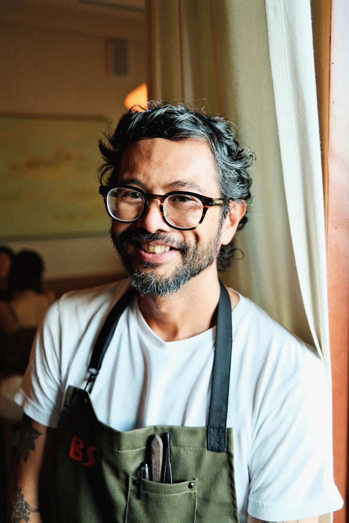 David Potes in a white T-shirt and olive-green apron.