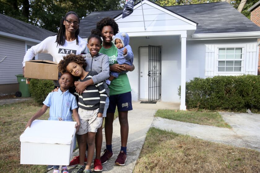 This image provided by Atlanta Land Trust shows Makeisha Robey, left, and her children posing in front of the home they purchased in 2020 through Atlanta Land Trust. (Atlanta Land Trust via AP)