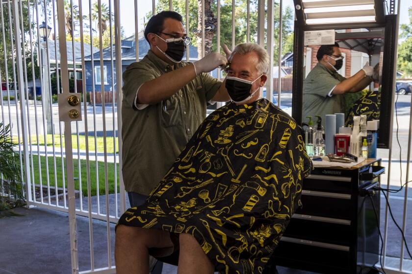 RIVERSIDE, CA - JULY 28, 2020: Owner Obie Figueroa cuts Matt Nelson's hair of San Dimas as the coronavirus pandemic has forced Figueroa to move his services outside at Obie's Barbershop & Shave on July 28, 2020 in Riverside, California. (Gina Ferazzi / Los Angeles Times)