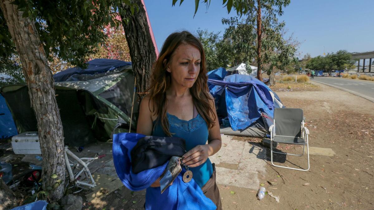 Jodi Samhat, 34, stands outside her tent at a homeless encampment along the Santa Ana River bed in Anaheim.