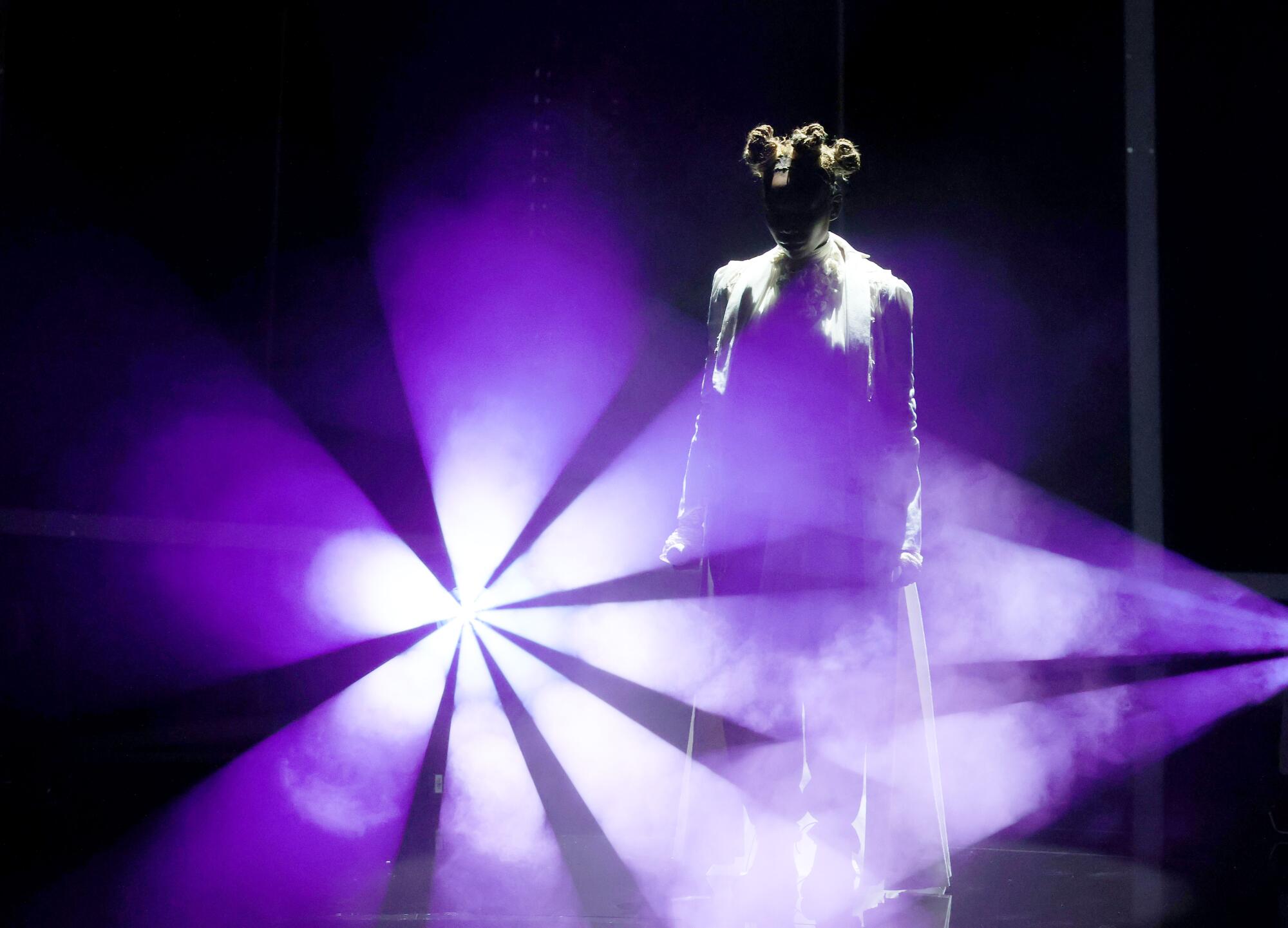 Brandy is silhouetted in a purple spotlight on stage.