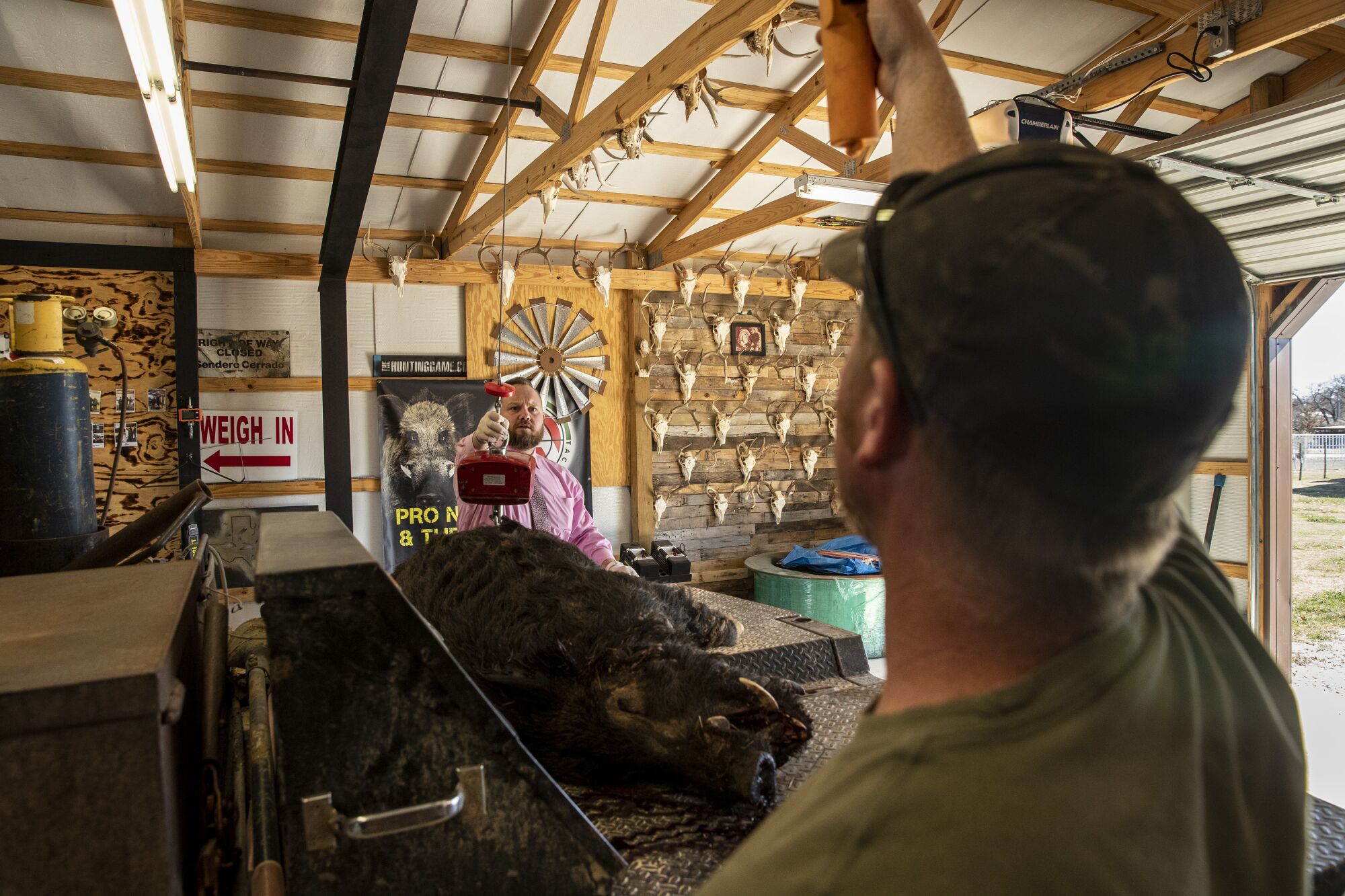 Adrian Ligon, right, helps Trey Hawkins weigh a hog in Wise County.
