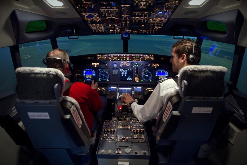 A picture taken on December 9, 2011 in Paris shows a pilot (R) assisting a man using a flight simulator in a reproduction of a Boeing 737 cockpit. The Flight Experience simulator is aimed at the general public and offers a variety of flight packages ranging from 30 to 90 minutes a range of 24.000 airports. AFP PHOTO JOEL SAGET (Photo credit should read JOEL SAGET/AFP via Getty Images)