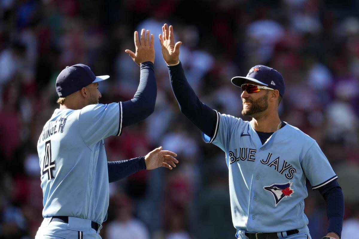 George Springer, left, and Kevin Kiermaier celebrate the Blue Jays' 12-11 victory over the Angels on Sunday in Anaheim.