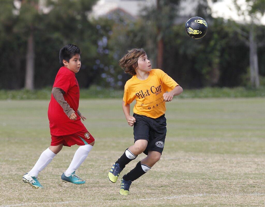 Pegasus' Nick Karahalios, right, heads the ball upfield while a Pomona player steps up.