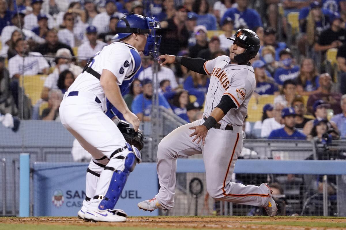 San Francisco Giants' Donovan Solano scores on a double by Thairo Estrada as Dodgers catcher Will Smith waits for the ball.